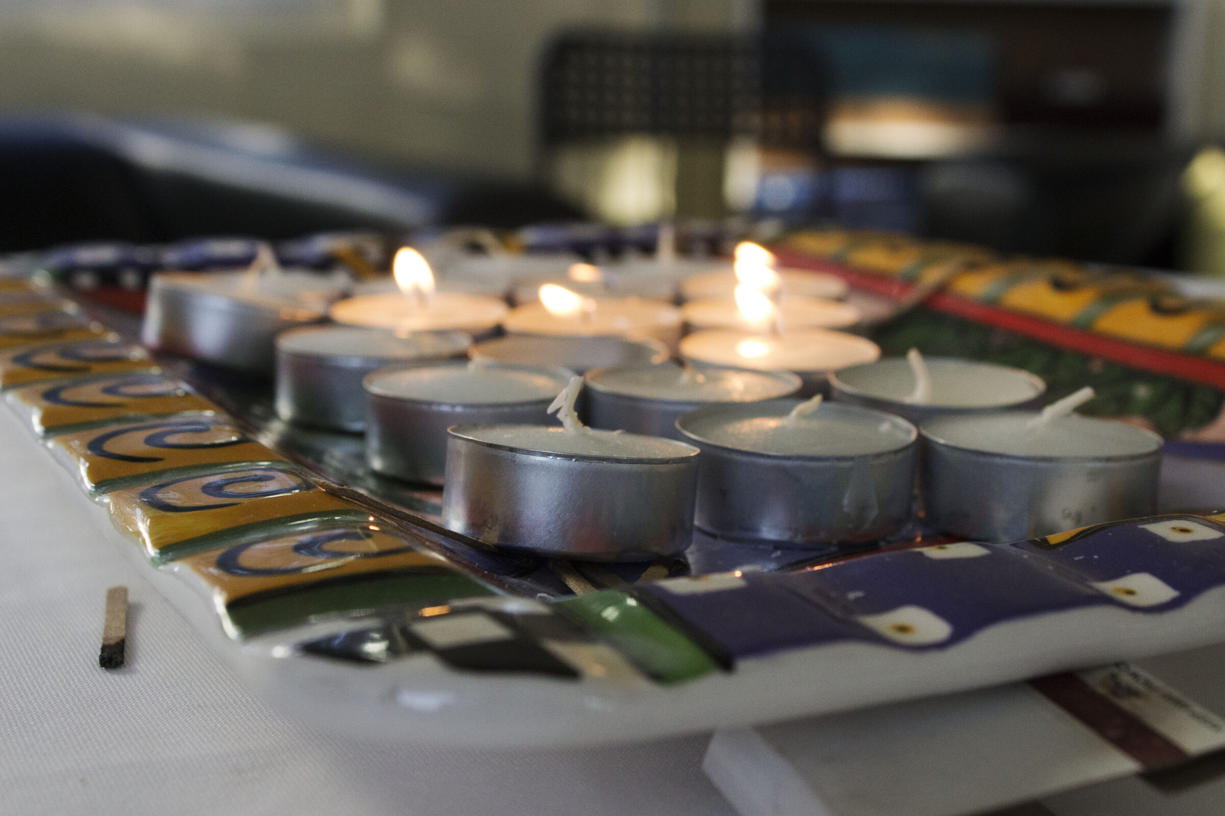 A close view of lit tealight candles in rows